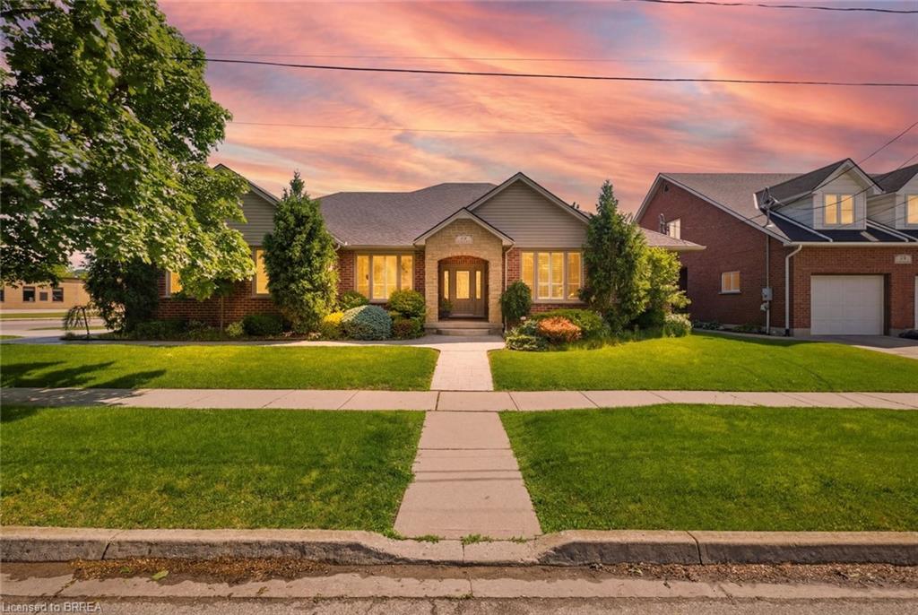 Brick bungalow front exterior at dusk with landscaped lawn and walkway at 74 Franklin Street, Brantford